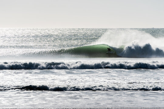 person inside the tube in the wave on the sea shore, high contrast
