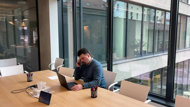 Young man emotionally communicating on the phone in the office