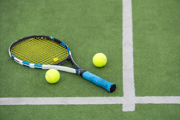 Tennis ball and racket on the ground of sunny outdoor grass tennis court. Summer, healthy lifestyle, sport and hobbies.
