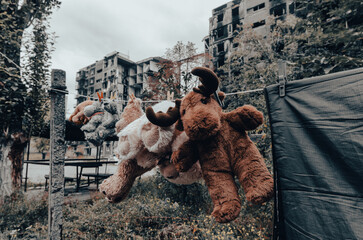 children's toys hang on a rope against the background of destroyed burnt houses in Ukraine