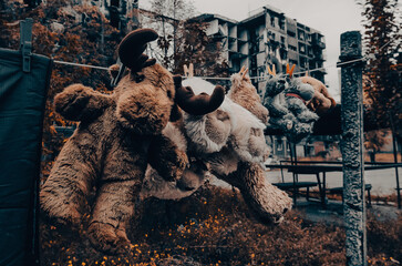 soft toys are dried after washing against the background of a burnt-out building in Mariupol