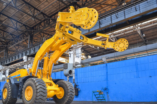 A huge wheel loader with an attached grab/manipulator for changing tires on dump trucks. Heavy construction machinery in industry.