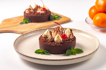 Delicious chocolate tart garnish with cherry and mint. Classic dessert. - 760444585