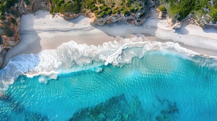 Fototapeta na wymiar An aerial view of waves washing onto a white sandy beach.