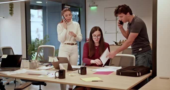 Dynamic office team deeply engaged in project analysis at a bustling workspace, showcasing their dedication and collaboration in a fast-paced environment.