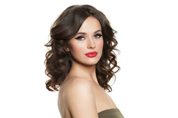 Fototapeta premium Pretty brunette female model with long wavy hair, makeup and healthy skin looking at camera on white background