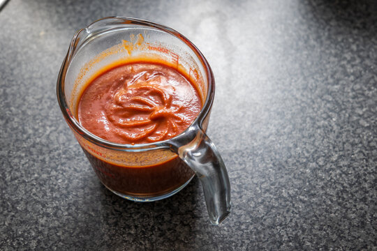 Stirring enchilada red sauce in glass measure jar
