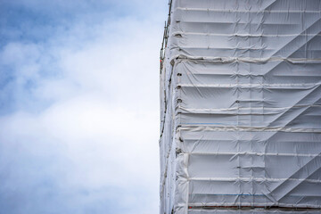 Flame retardant scaffold sheeting wrapped apartments building during insulation in england uk - obrazy, fototapety, plakaty