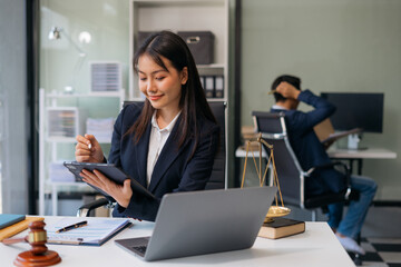 Female Legal counsel working with paperwork on his desk in office workplace working with tablet computer. Justice and law concept.