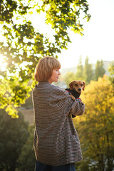Owner walking with dog together in park outdoors, summer vacation, Adorable domestic pet concept, Friendship between human and their pet. Dachshund in sweater High quality photo