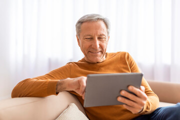 Relaxed senior man using digital tablet at home