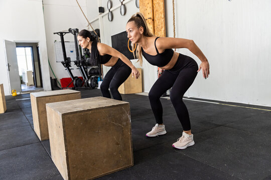 Fitness couple are performing box jumps at gym, plyometric exercise