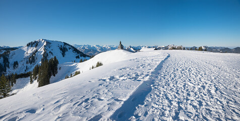 snowy Wallberg summit with chapel and view to Setzberg mountain, upper bavaria