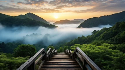 Foto op Canvas a wooden walkway on top of the mountains with the beauty of cloud-covered mountains and sunrise. © MINHO