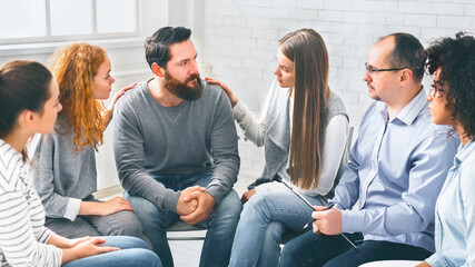 Therapy Group Members Comforting Upset Man On Community Meeting In Rehab