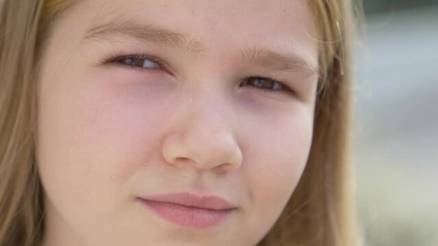 Portrait of a beautiful teenage girl smiling and squinting at the sun. Pediatrics and Dentistry for Children. A happy and healthy childhood.