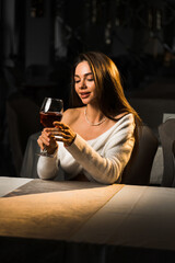 Young woman holding a glass of wine.Woman drinking wine in a restaurant.Red wine concept