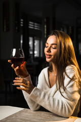 Young woman holding a glass of wine.Woman drinking wine in a restaurant.Red wine concept