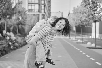 young mother and son smiling looking at the camera in modern residential complex. Having fun together, happy parenting, new home concept. Bright summer day in the urban background. High quality photo