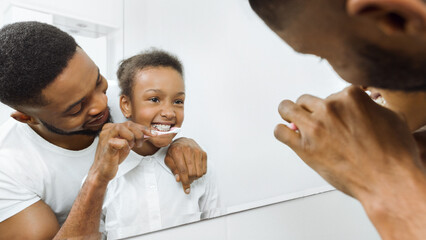 Caring father brushing daughter's teeth in the bathroom