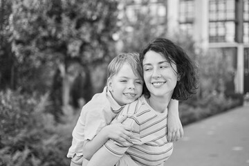 young mother and son smiling looking at the camera in modern residential complex. Having fun together, happy parenting, new home concept. Bright summer day in the urban background. High quality photo
