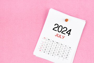 July 2024 calendar page and wooden push pin on pink background.