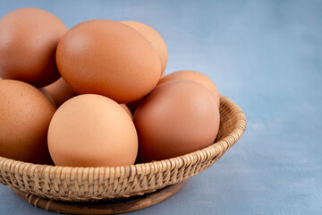 Freshness chicken eggs in wooden weave basket on blue wooden.