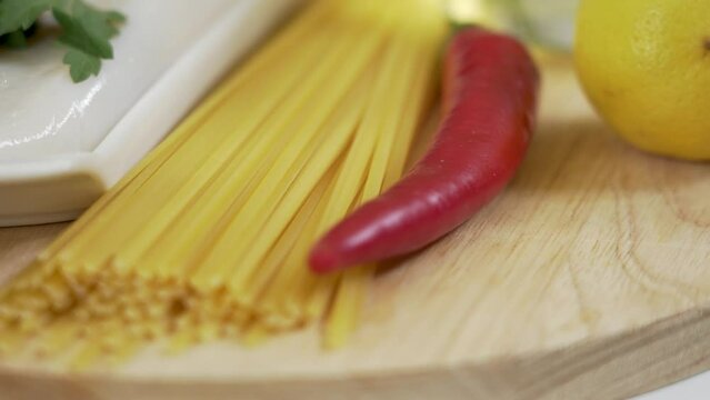 Dry pasta linguine and raw squid fillet with other ingredients for cooking pasta