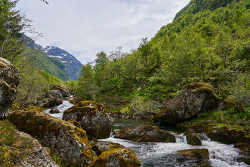 Fototapeta na wymiar waterfall along the hiking trail towards the beautiful Bondhus Vatnet lake in the highlands of Norway, popular travel destination for nature lovers and hikers.