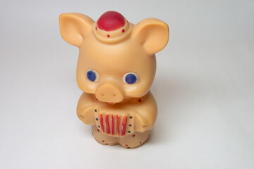 cute piglet with big blue eyes toy, in little hat and colored polka dots jumpsuit playing at...