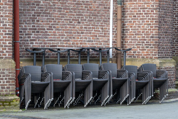 large quantities of stacked chairs in front of brick wall