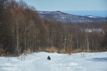 Winter entertainment, sledding down the hill. Winter landscape.