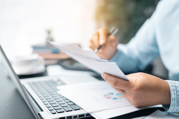 Business woman working on documents looking concentrated with briefcase on table. Businesswoman is deeply reviewing a financial report for a return on investment or investment risk analysis.