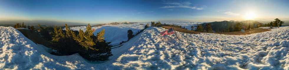 A panoramic view of a snowy mountain with a red and white flag in the foreground