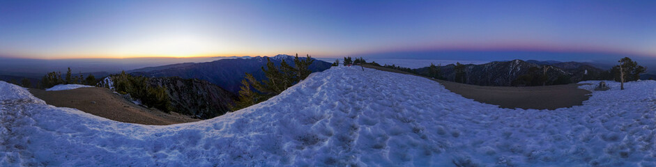 A panoramic view of a snowy mountain with a beautiful sunset in the background