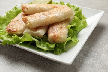 Delicious fried spring rolls on grey table, closeup