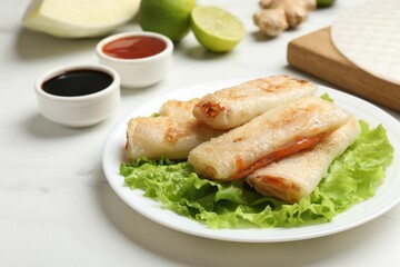 Delicious fried spring rolls served on white marble table