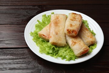 Delicious fried spring rolls on wooden table