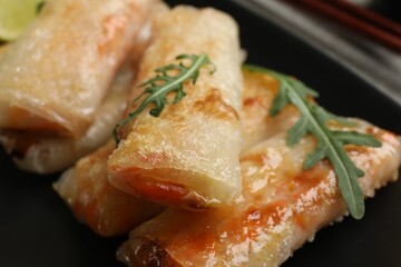 Tasty fried spring rolls with arugula on plate, closeup