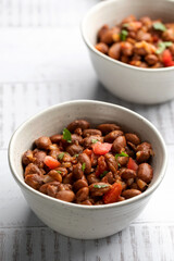 Food dish made of beans, tomatoes, and cilantro on a wooden table