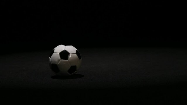 black and white soccer ball crits in slow motion on a black background close-up. High quality FullHD footage