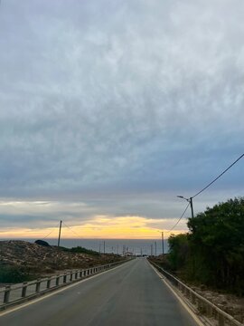 Empty road to the the ocean, asphalt road, sunset ocean horizon background