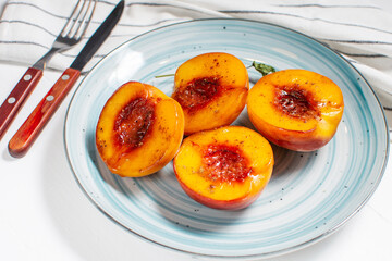 Naklejka na ściany i meble Baked peaches with honey and cinnamon in a ceramic plate. summer dessert