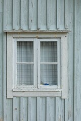 Closeup of white framed window on a green painted wooden wall.