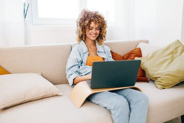 Smiling woman using laptop at home: Modern lifestyle and freelance job in a cozy living room