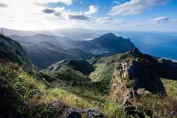 Naklejka premium Overlook Keelung volcano groups from peak, grass covered mountains and ocean just nearby, sunlight shine on it, in Jiufen, Jinguashi, New Taipei City, Taiwan.