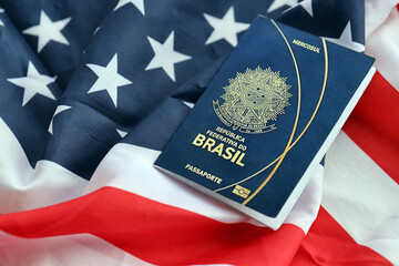 Blue Brazilian passport on United States national flag background close up. Tourism and diplomacy concept
