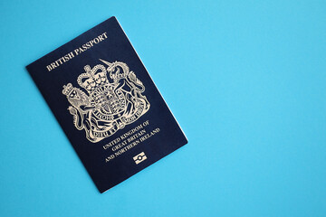 Blue British passport on blue background close up. Tourism and citizenship concept - obrazy, fototapety, plakaty