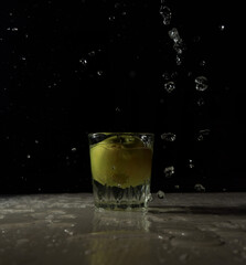 Green apple in a glass of clear water on black background