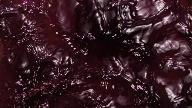 Beautiful splashes of red wine and cherry juice in slow motion. Close-up. Liquid texture